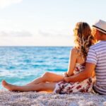 young-couple-in-love-sitting-on-the-beach-PRRSRHJ-ongb91doc24h8h77833tyck4oz3slncjeuu90m91gg